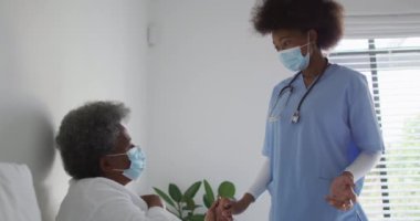Mutlu Afro-Amerikan kadın fizyoterapist yaşlı kadın hastaların evde egzersiz yapmasına yardım ediyor. Üst düzey sağlık ve tıbbi fizyoterapi tedavisi.