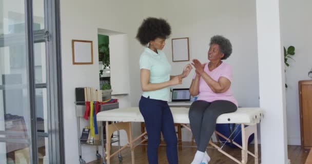 Fisioterapeuta Afro Americana Usando Máscara Facial Ajudando Paciente Idosa Exercitar — Vídeo de Stock