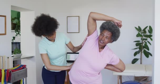 快乐的非洲裔美国女性理疗师帮助老年女性病人在家锻炼 老年人保健和医疗理疗治疗 — 图库视频影像