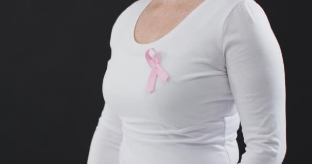 一个女人胸部的中间部分 在黑色背景的衬托下露出粉红色的缎带 乳腺癌意识概念 — 图库视频影像