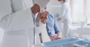 Modern diş kliniğinde yüz maskesi takan çift ırklı kadın dişçi erkek hastayı hazırlıyor. covid 19 salgını sırasında sağlık ve dişçilik sektörü.