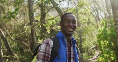 Kırsal kesimde yürüyüş yaparken ormanda gülümseyen Afrikalı Amerikalı bir adamın portresi. sağlıklı, aktif yaşam tarzı ve boş zaman.