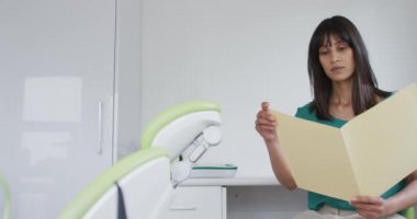 Modern diş kliniğinde elinde belgeler tutan melez kadın hastaların portresi. Sağlık ve dişçilik sektörü.