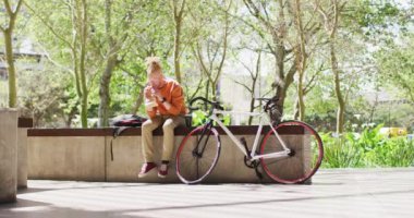 Albino Afro-Afrikalı Amerikalı rastalı adam bisikletli sandviçle parkta oturuyor. # Şehirde gezip tozuyor #.