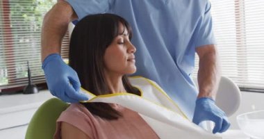 Modern diş kliniğinde yüzü maskeli beyaz erkek dişçi gülümseyen kadın hasta hazırlıyor. covid 19 salgını sırasında sağlık ve dişçilik sektörü.