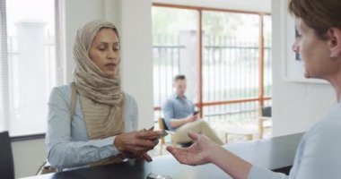 Modern diş kliniğindeki resepsiyonda çift ırklı bir kadın kredi kartıyla ödeme yapıyor. Sağlık ve dişçilik sektörü.
