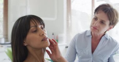 Modern diş kliniğinde kadın hastayla konuşan beyaz kadın diş hemşiresi. Sağlık ve dişçilik sektörü.