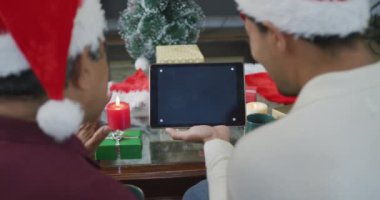 Baba ve çift ırklı oğul noel videolarını boş ekranlı ve kopya alanlı tablet bilgisayarına yüklüyorlar. Noel, şenlik ve iletişim teknolojisi.