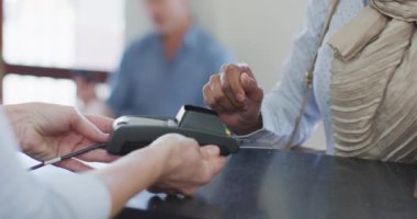 Modern diş kliniğindeki resepsiyonda çift ırklı bir kadın kredi kartıyla ödeme yapıyor. Sağlık ve dişçilik sektörü.