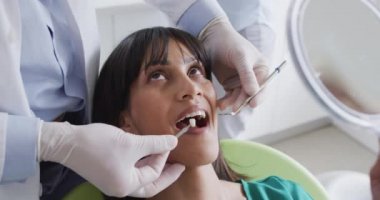 Erkek dişçi, modern diş kliniğinde kadın hastayı muayene ediyor. Sağlık ve dişçilik sektörü.
