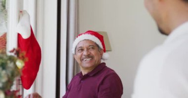 Neşeli son sınıf öğrencisi pencereye Noel çorabı asıyor ve oğlunu evde okşuyor. Noel ailesi ve şenlik.