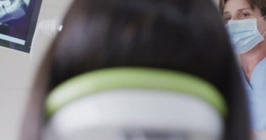 Modern diş kliniğinde yüz maskesi takan beyaz dişçi kadın hasta hazırlıyor. covid 19 salgını sırasında sağlık ve dişçilik sektörü.
