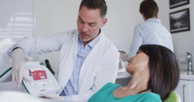 Modern diş kliniğinde dişlerini muayene eden dişçisi olan beyaz bir erkek diş hekimi. Sağlık ve dişçilik sektörü.