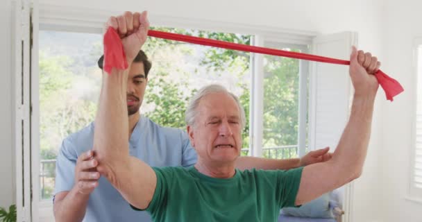 Physiothérapeute Mâle Naissante Avec Homme Âgé Caucasien Tenant Une Bande — Video