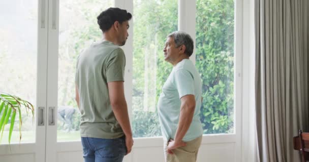 Starší Muž Diskutuje Synem Zatímco Stojí Okna Obývacím Pokoji Doma — Stock video