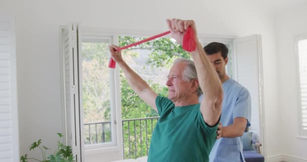 Mouvement Lent Homme Âgé Exerçant Avec Bande Résistance Par Physiothérapeute — Video