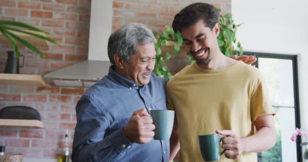 快乐的父亲和儿子一边烘焙咖啡杯 一边在家里的厨房里消闲 家庭生活方式 饮料和交流 — 图库视频影像