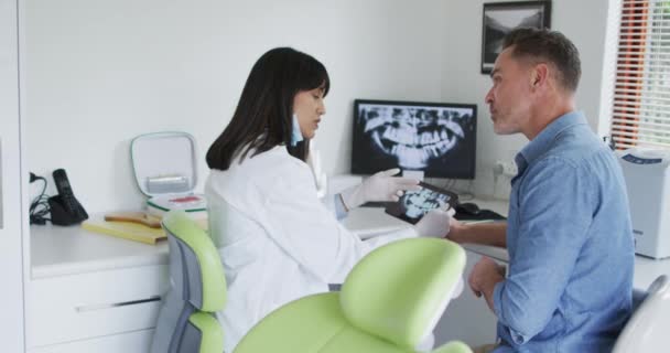 Dwurasowy Dentysta Masce Badający Zęby Męskiego Pacjenta Nowoczesnej Klinice Stomatologicznej — Wideo stockowe