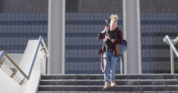 有思想的白化病美国人 带着可怕的头发骑着自行车下楼 在城市里走来走去 — 图库视频影像