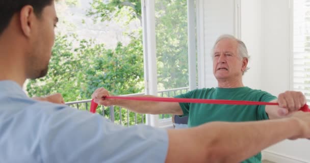 Běloch Který Drží Odbojovou Skupinu Cvičí Mužským Fyzioterapeutem Pečovatelském Domě — Stock video