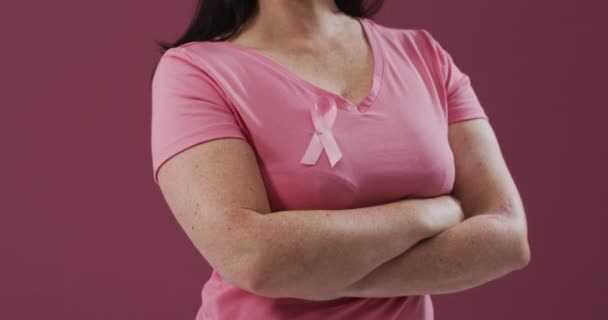 腕を持つ女性は Tシャツの上にピンクの乳がん啓発リボンを身に着けて渡った 乳がんの認知の象徴は — ストック動画