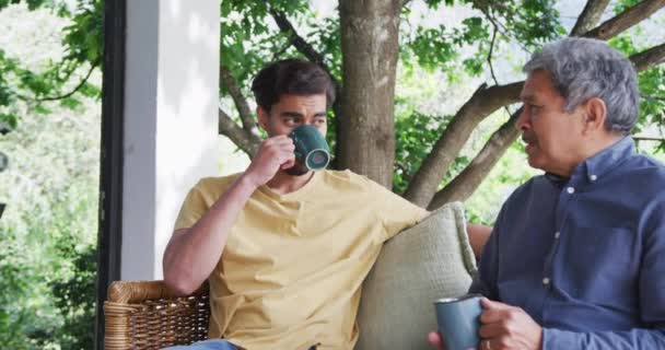 年轻人一边喝咖啡 一边听父亲在院子里的谈话 家庭生活方式 饮料和交流 — 图库视频影像