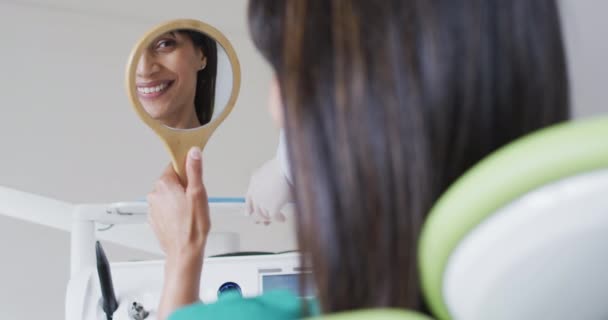 Mulher Biracial Olhando Para Dentes Sorrindo Espelho Clínica Odontológica Moderna — Vídeo de Stock