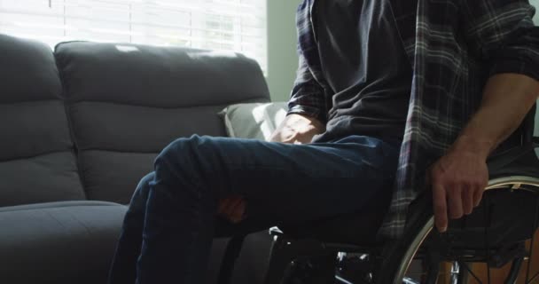 車椅子の白人障害者がリビングルームのソファに座っている 身体障害のある国内生活 — ストック動画