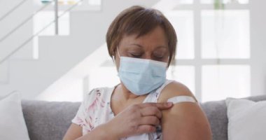 Yüzü maskeli Afrikalı Amerikalı son sınıf öğrencisi kadın kollarında bandaj olduğunu gösteriyor. covid 19 salgını sırasında emeklilik sağlık ve yaşam tarzı.