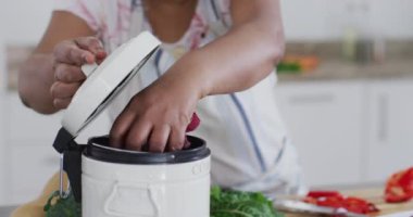 Afro-Amerikalı son sınıf öğrencisi kadın mutfakta yemek hazırlıyor, sebze atıkları pişiriyor ve gülümsüyor. sağlıklı, aktif emeklilik yaşam tarzı.