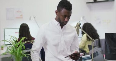 Modern ofiste koridorda yürürken akıllı telefondan konuşan gülümseyen melez bir iş kadını. iş ve işyeri.