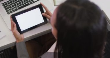 Çift ırklı iş kadını masasında oturuyor, modern ofiste kopya alanı olan tablet kullanıyor. iş ve işyeri.