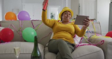 Mutlu Afro-Amerikan son sınıf öğrencisi kadın parti üfleyicisi kullanıyor ve yılbaşı arifesinde video çekiyor. emeklilik, gelenek ve yaşam tarzı, evde iletişim teknolojisiyle kutlama.