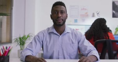 Afrika kökenli Amerikalı iş adamı masamızda oturmuş, modern ofiste video görüşmesi yapıyor. iş ve işyeri.