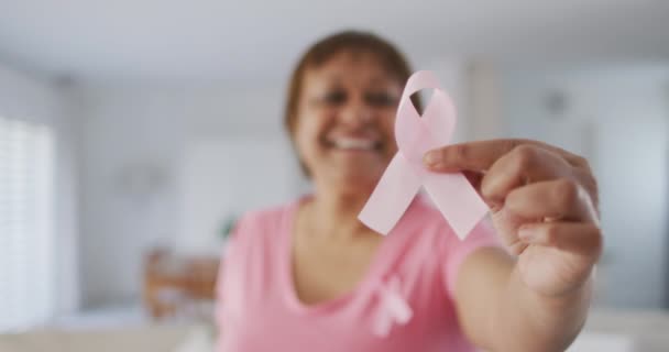 ピンクのTシャツにピンクの乳がんリボンをつけたアフリカ系アメリカ人のシニア女性が微笑む 高齢女性のライフスタイルと乳がんの認知度向上キャンペーン — ストック動画
