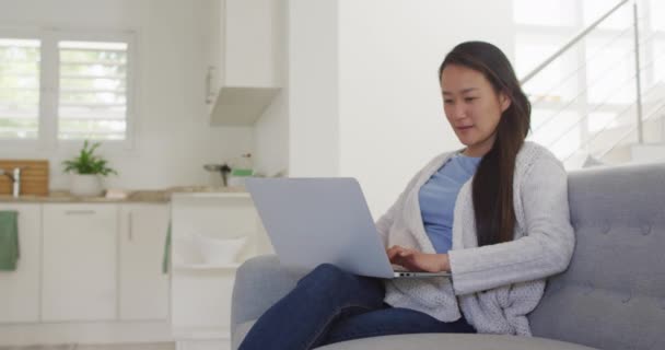 快乐的亚洲女人坐在沙发上 在家里带着笔记本电脑休息 生活方式和在家里用科技放松 — 图库视频影像