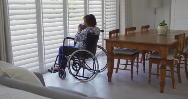 Αφροαμερικανή Ηλικιωμένη Γυναίκα Αναπηρικό Καροτσάκι Που Κοιτάει Έξω Από Παράθυρο — Αρχείο Βίντεο