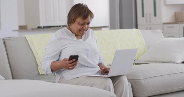 Šťastná Americká Seniorka Sedící Gauči Chytrým Telefonem Laptopem Usmívající Důchodový — Stock video