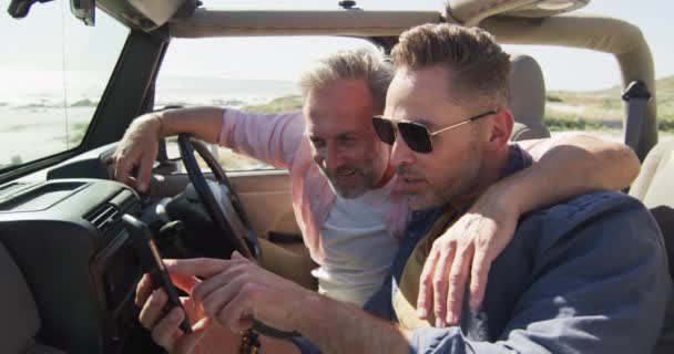 Kafkasyalı Mutlu Erkek Çift Akıllı Telefon Kullanarak Arabada Oturuyor Kumsalda — Stok video