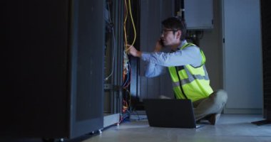 Akıllı telefon ve dizüstü bilgisayar sunucusu kullanan Asyalı bir erkek. bilgi teknolojisi, veri işleme ve bilgisayar sunucuları.