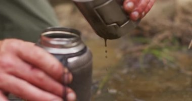 Kafkas erkek hayatta kalanların elleri su içmek için filtre şişesine su döküyor. Keşif, seyahat ve macera, doğada hayatta kalma uzmanı..