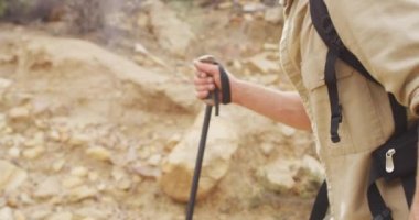 Beyaz erkek hayatta kalanların orta kesiminde sırt çantası ve bastonlarıyla vahşi doğada yürüyüş yapıyorlar. Keşif, seyahat ve macera, doğada hayatta kalma uzmanı..