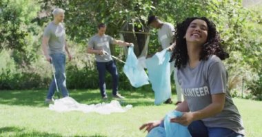Gönüllü tişörtlü, atık poşetlerine dışarıda plastik atık koyan mutlu arkadaş grubu. Çevre koruma gönüllüleri kırsal alanda temizlik yapıyor..