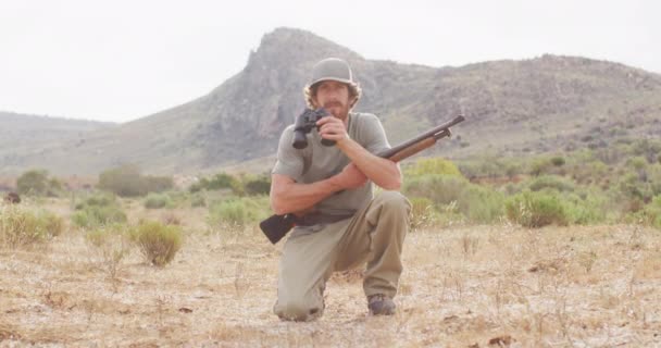 Kneeling Caucasian Male Survivalist Holding Hunting Rifle Looking Using Binoculars — Stock Video