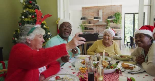 Diverse Seniorvenner Julemandshatte Kigger Smartphone Griner Ved Julebordet Pensionering Livsstil – Stock-video