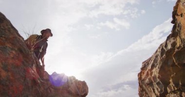 Sırt çantalı, beyaz sakallı, erkek, vahşi doğada kayalık dağ geçidinde atlıyor. Keşif, seyahat ve macera, doğada hayatta kalma uzmanı..