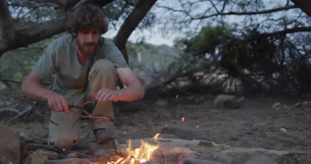 Happy Bearded Caucasian Male Survivalist Adding Kindling Fire Camp Wilderness — Stock Video