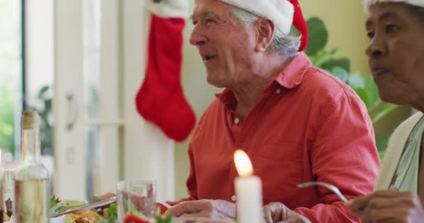 Afwisselende Oudere Man Vrouw Kerstmutsen Luisteren Lachen Aan Kerstdiner Tafel — Stockvideo