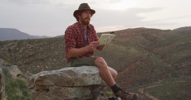 Caucasian Male Survivalist Sitting Mountain Peak Wilderness Holding Map Compass — Stock Video