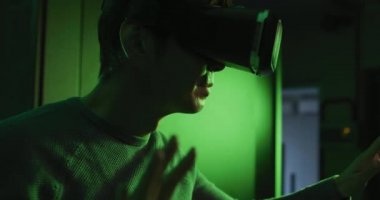 Bilgisayar sunucusu tarafından VR kulaklık takan Asyalı bir adam. bilgi teknolojisi, bağlantı, veri işleme ve bilgisayar sunucuları.